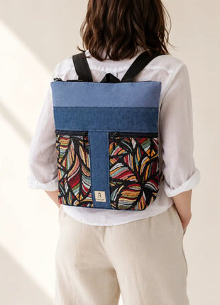 Mujer con Mochila Sullana estampada hecha a mano en Bilbao con tejido de hojas multicolor en fondo negro, regalo original para mujer unico e irrepetible
