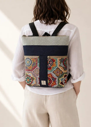 Mujer con Mochila Sullana estampada hecha a mano en Bilbao con tejido de mandalas multicolor en tonos ocre y verde, regalo original para mujer unico e irrepetible