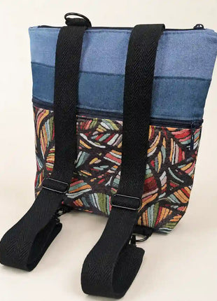 Mochila Sullana estampada hecha a mano en Bilbao con tejido de hojas multicolor en fondo negro y correas negras regulables, regalo original para mujer unico e irrepetible