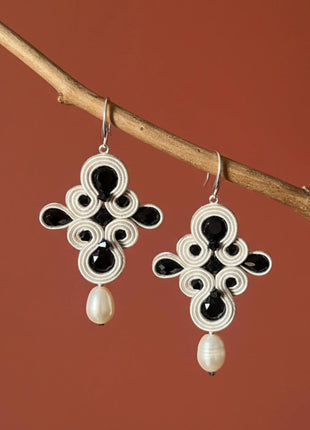 Pendientes Dona Macarena de soutache crema con cristales negros y perla natural hechos a mano en Bizkaia, colgando de rama