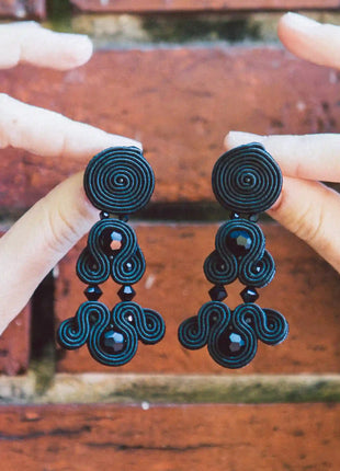 Manos sosteniendo pendientes Versalles de soutache negro hechos a mano en Bizkaia, regalo original para mujer unico e irrepetible