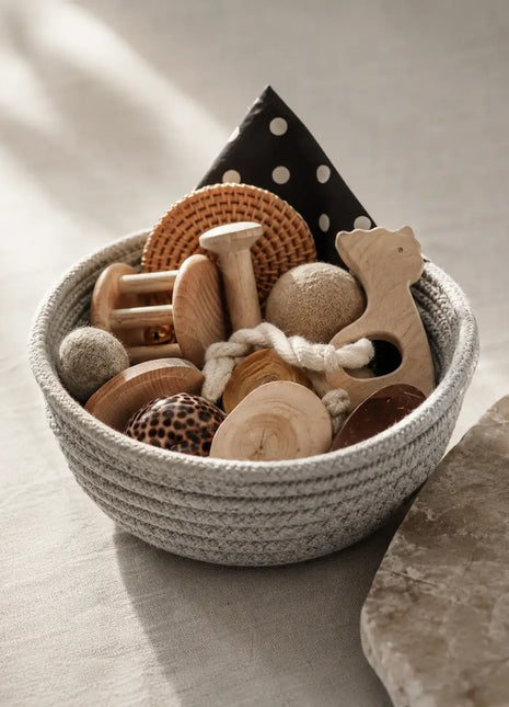Cesta Tesoros Natura Montessori en color gris con juguetes sensoriales de madera y materiales naturales — regalo original para bebés